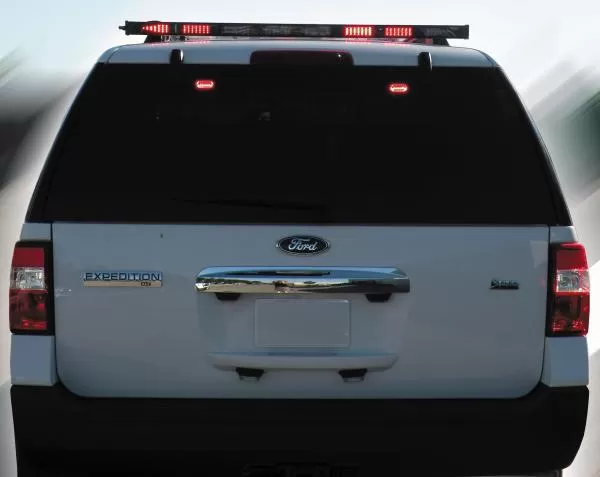 Rear of a white Ford Expedition with the roof-mounted arrow bar showing red segments illuminated