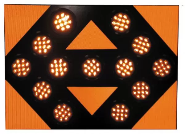 Close-up of the lit face, thirteen amber LED modules glowing against the orange reflective panel