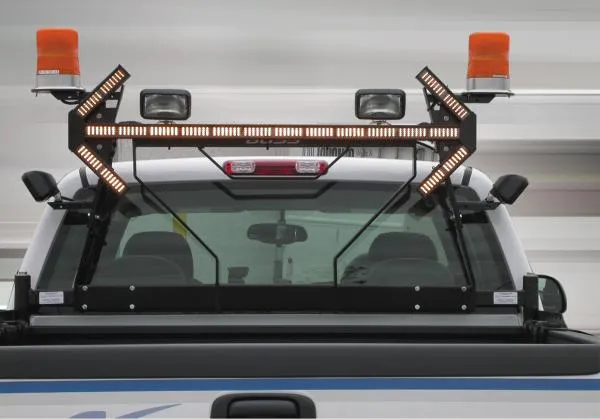 Amber light stick lit on the cab rack of a white truck between two rotating beacons and work lights