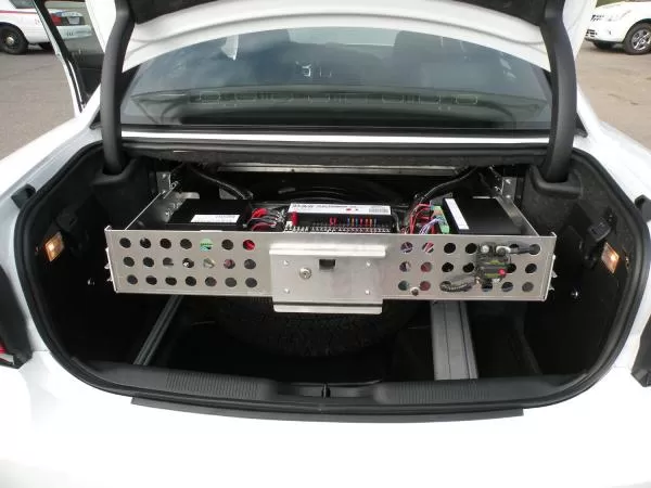 Rear view of the slide-out tray carrying a wired D&R power module and fuse block across the trunk