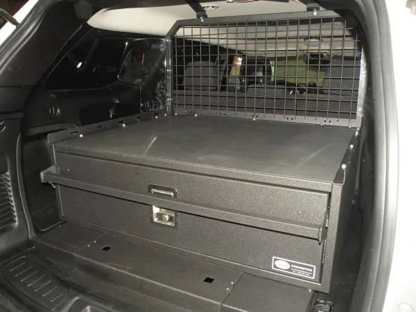 Closed drawer front with recessed pull handle and keyed lock, mesh cargo partition behind