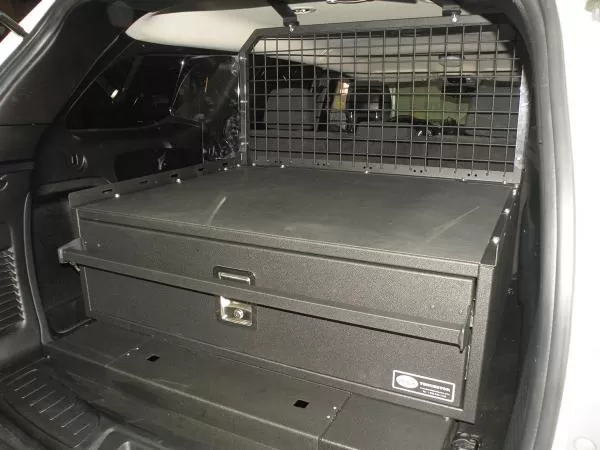 Closed drawer front with recessed pull handle and keyed lock, mesh cargo partition behind