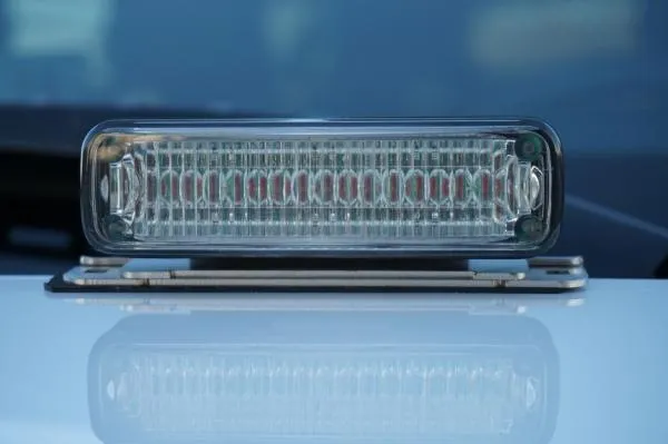 Straight-on look at a deck mounted clear module, lens optics and low bracket reflected in the white paint