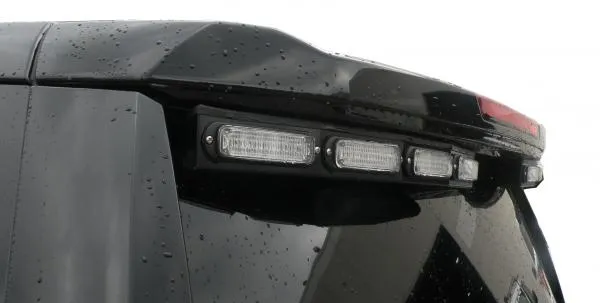 Close-up of the unlit clear lenses in their black bracket under the spoiler edge of a Chevy Tahoe