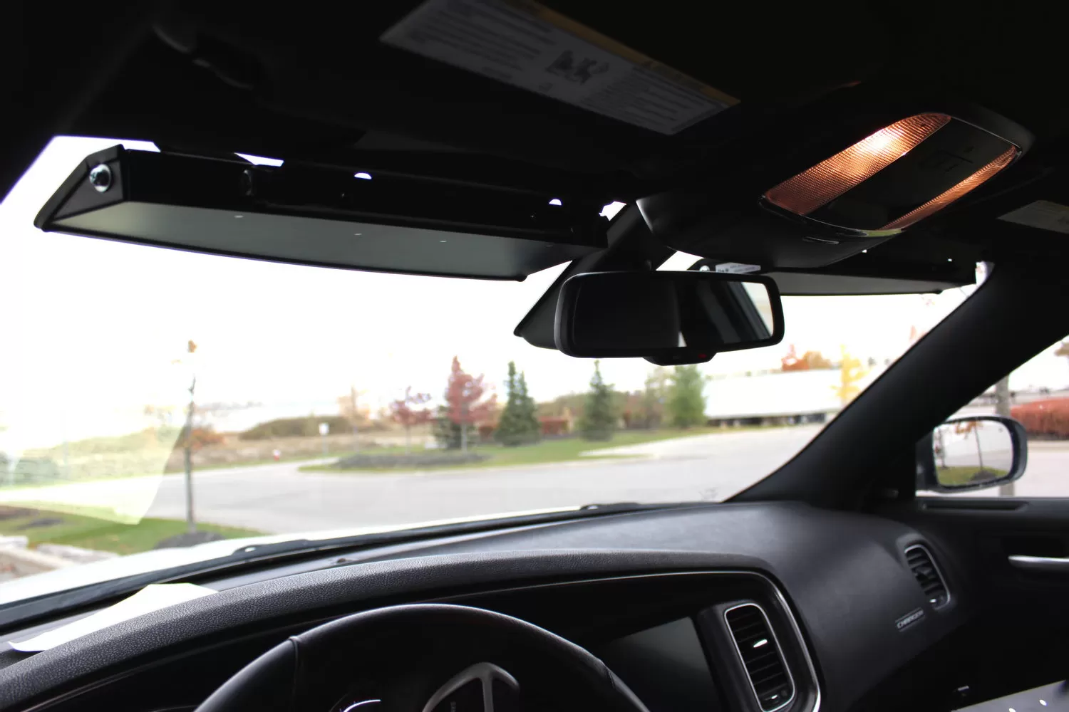 Cabin view looking up at the low-profile visor bar fitted to the headliner beside the rear-view mirror
