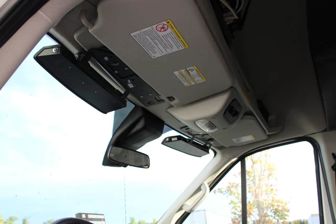 Looking up at a Transit windshield header where the black bar bracket sits beside the sun visor