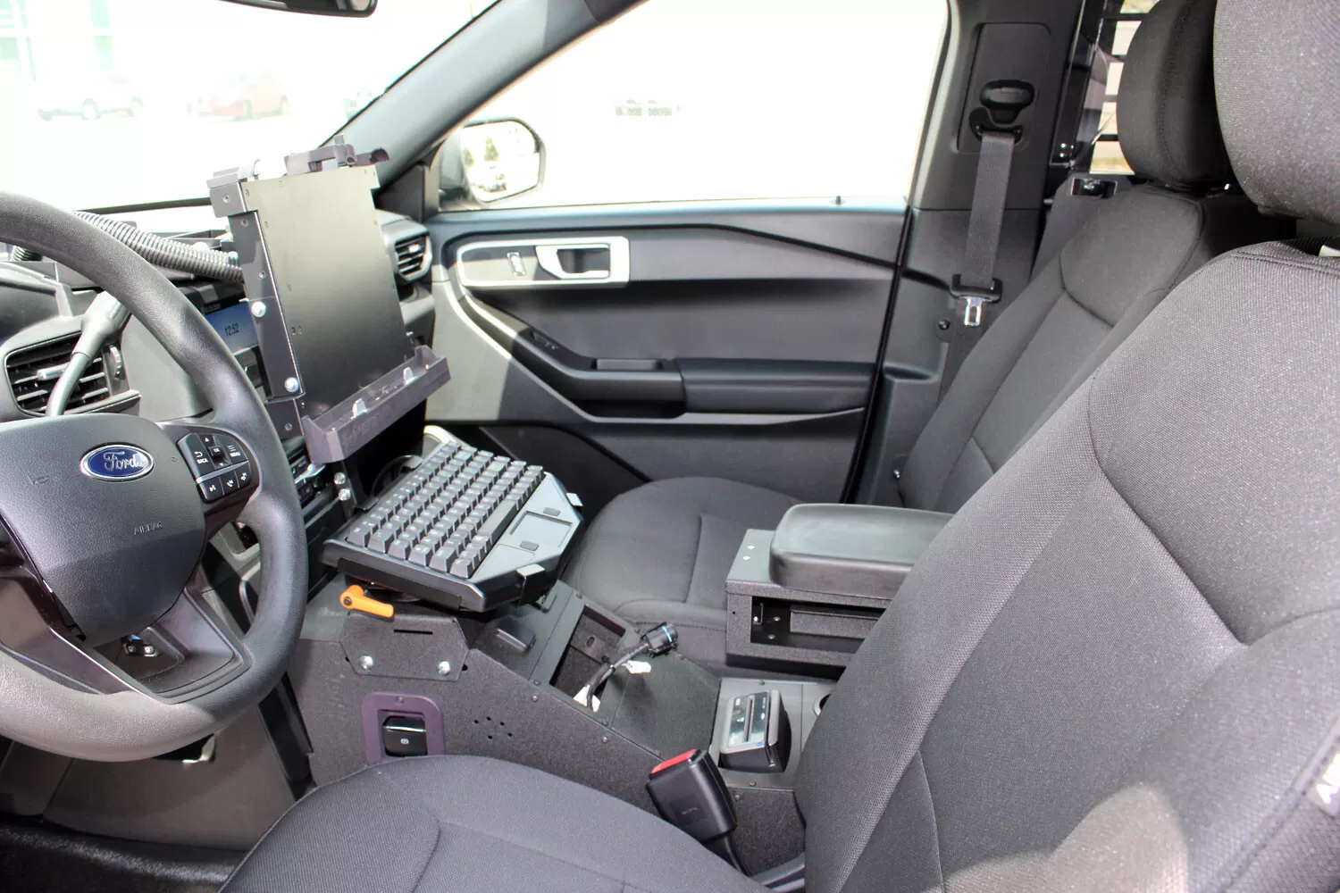 Console installed in a Ford Utility cruiser with laptop keyboard mount and armrest, seen from the passenger door
