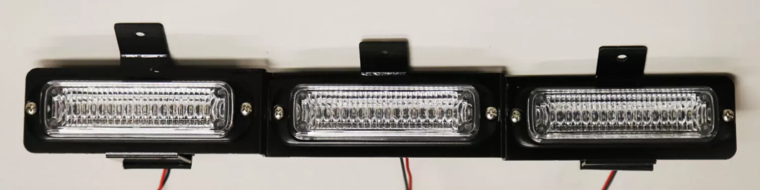 Bare three-module assembly on its black mounting bracket with wiring pigtails, straight-on and unlit