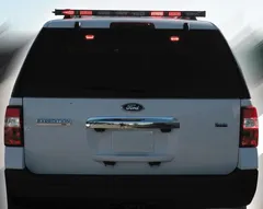 Rear of a white Ford Expedition with the roof-mounted arrow bar showing red segments illuminated