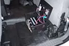 Lid open on the floor-mounted box, revealing the fuse block, relays and bundled wiring harness inside