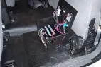 Lid open on the floor-mounted box, revealing the fuse block, relays and bundled wiring harness inside