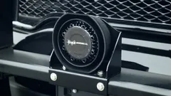 Speaker bolted to a black bracket on a push bumper directly in front of a vehicle grille