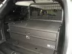 Closed drawer front with recessed pull handle and keyed lock, mesh cargo partition behind