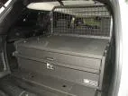 Closed drawer front with recessed pull handle and keyed lock, mesh cargo partition behind