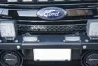Slim modules mounted on the licence plate bar of a Ford grille between two larger LED lamps