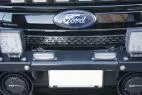 Slim modules mounted on the licence plate bar of a Ford grille between two larger LED lamps