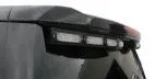 Close-up of the unlit clear lenses in their black bracket under the spoiler edge of a Chevy Tahoe