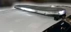 Bar on a white roof with clear lenses and white LEDs showing, low profile against a wet painted panel