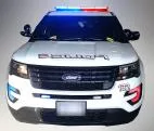 Front of a white Ford Explorer police unit with the roof bar, grille and bumper LEDs flashing