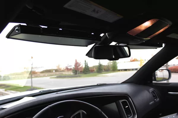 Cabin view looking up at the low-profile visor bar fitted to the headliner beside the rear-view mirror