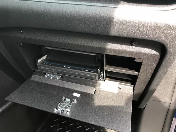Angled close-up of a Brother printer seated in the open glove box with the latch on the inside of the door